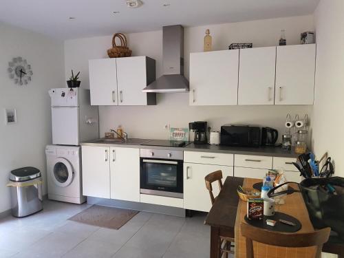 cocina con armarios blancos, mesa y fogones en Clos des lys, en Vittel