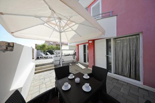 a patio with a black table and a white umbrella at Villa Pino with Pool, Sauna & Jacuzzi in Petrcane
