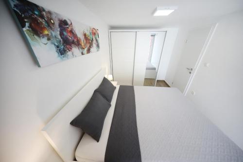 a bedroom with a white bed with a black pillow at Villa Pino with Pool, Sauna & Jacuzzi in Petrcane
