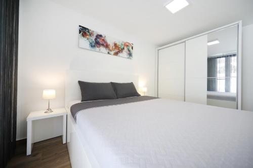 a white bedroom with a large bed and a window at Villa Pino with Pool, Sauna & Jacuzzi in Petrcane