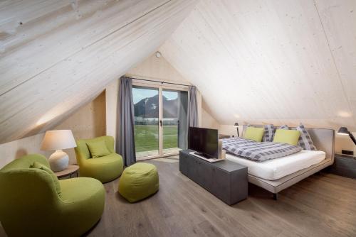 Schlafzimmer mit einem Bett, einem TV und Stühlen in der Unterkunft pure mountain BASE in Erpfendorf