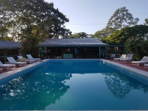 a swimming pool with chairs and a building at Cabañas Los Troncos in Ituzaingó