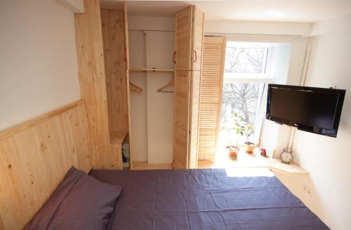 a bedroom with a bed and a tv and a window at A cozy wooden studio in a heart of Kharkiv in Kharkiv