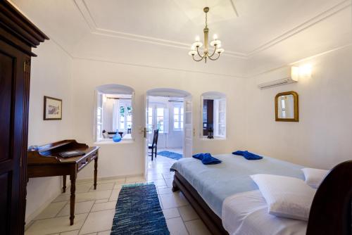 Chelidonia Traditional Villas في أويا: غرفة نوم بسرير ومكتب وبيانو
