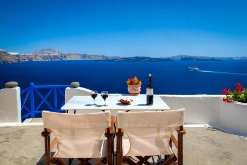 a table with two glasses of wine and a view of the ocean at Chelidonia Traditional Villas in Oia