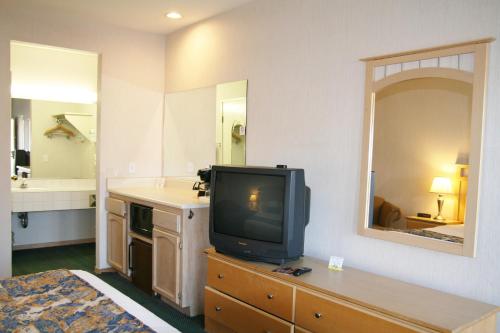 a room with a tv on a dresser with a bathroom at Days Inn by Wyndham Rocklin/Sacramento in Rocklin