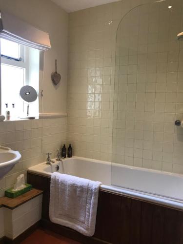a bathroom with a bath tub and a sink at Bells Cottage in Alderton