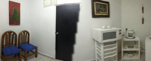 um quarto com uma porta preta e uma televisão e cadeiras em Brisas 54634 em Monterrey