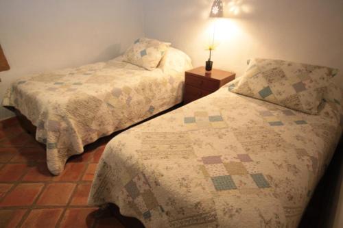 a bedroom with two beds and a lamp on a table at Hotel Boutique Quinta Tibigaro in San Vicente de Chucurí