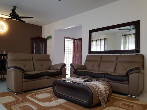 a living room with two couches and a mirror at Anjung Homestay in Sepang