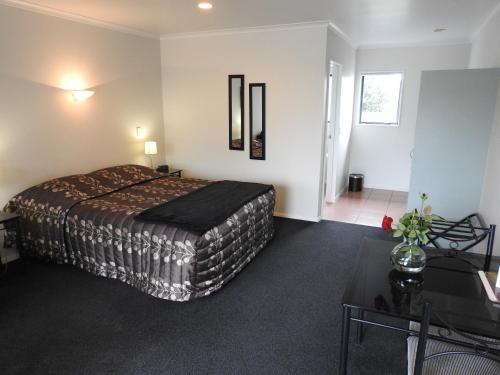 um quarto de hotel com uma cama e uma mesa em Tudor Lodge Motel em Hawera