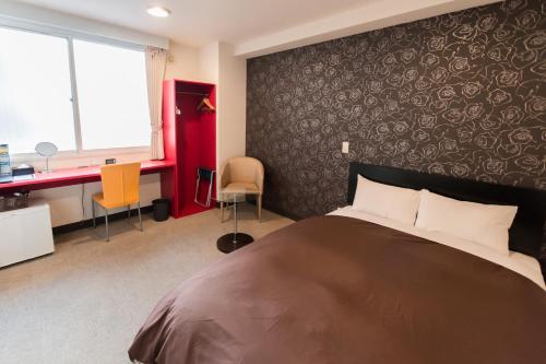 um quarto com uma cama, uma secretária e uma janela em Frame Hotel Sapporo em Sapporo