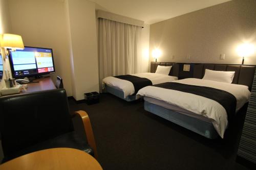 霧島市にあるアパホテル鹿児島国分のベッド2台とテレビが備わるホテルルームです。