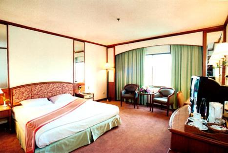 a hotel room with a bed and a desk at The Regency Hotel Hatyai in Hat Yai