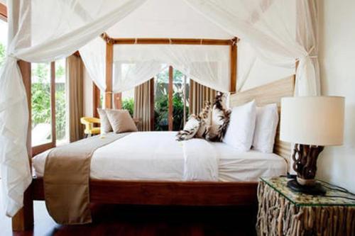 a bedroom with a white bed with a canopy at Villa Anema Umalas in Seminyak