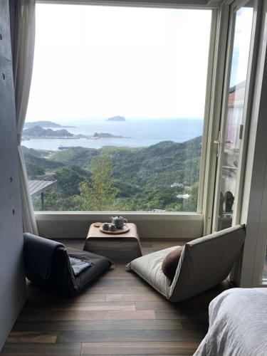 a room with a large window with chairs and a table at Something Easy Inn in Jiufen