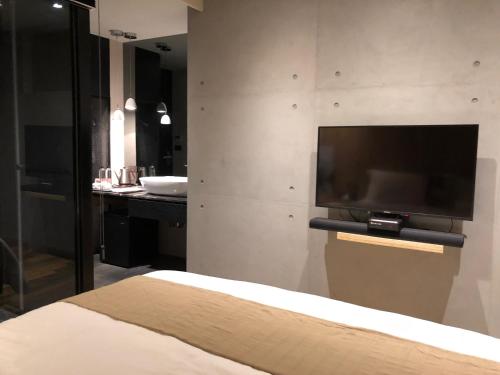 a bedroom with a flat screen tv on a wall at Something Easy Inn in Jiufen