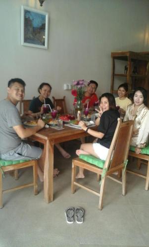 a group of people sitting around a wooden table at Luxury 3BR Infinity Jungle View Aashaya Villa Ubud in Ubud