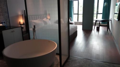 a bedroom with a bed and a tub in a room at 柏高酒店-深圳公明广场地铁站店 in Bao'an