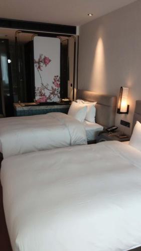 two beds in a hotel room with white sheets at 柏高酒店-深圳公明广场地铁站店 in Bao'an