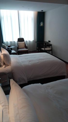 a hotel room with two beds and a chair at 柏高酒店-深圳公明广场地铁站店 in Bao'an