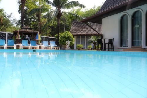 a large swimming pool with blue chairs and a house at Chalong Palm Residence in Chalong 