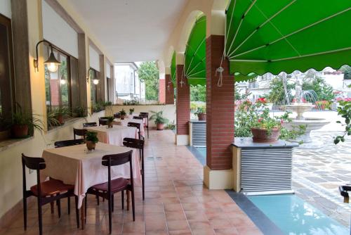 a restaurant with tables and chairs and green umbrellas at Hotel Reginella in SantʼAgata sui Due Golfi