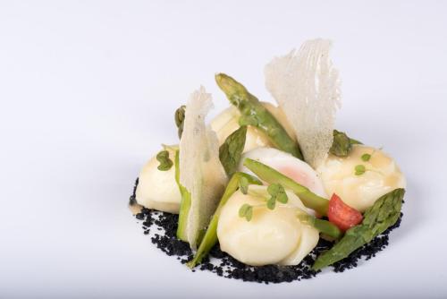 a dish of food with vegetables on a white background at Hotel Eira in Bormio