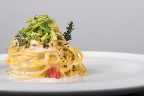 a plate of pasta with broccoli and a salad at Hotel Eira in Bormio