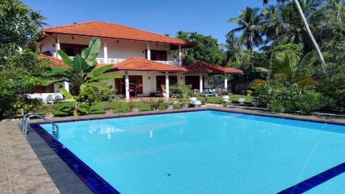 a swimming pool in front of a house at Siroma Villa in Bentota