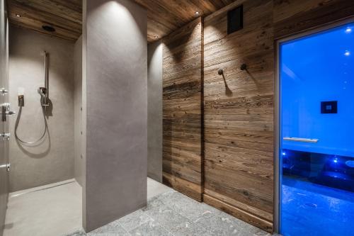 a bathroom with a shower with a wooden wall at Chalet Roenn in Colfosco