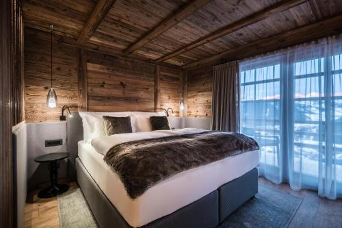 a bedroom with a large bed and a large window at Chalet Roenn in Colfosco