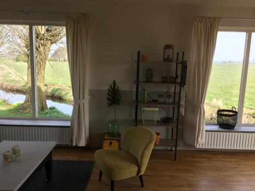a living room with two windows and a chair and a table at Wide ie Grou in Nes
