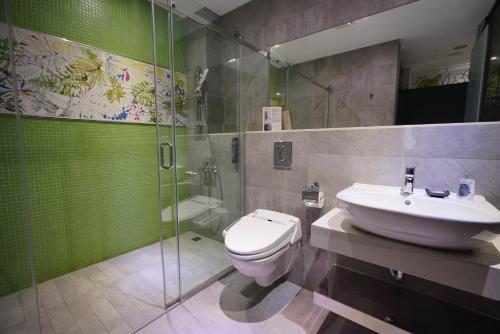 
a bathroom with a toilet, sink, and mirror at 3 Door Hotel in Tainan
