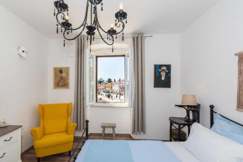 - une chambre avec un lit et une chaise jaune dans l'établissement Skipper Suites, à Novigrad