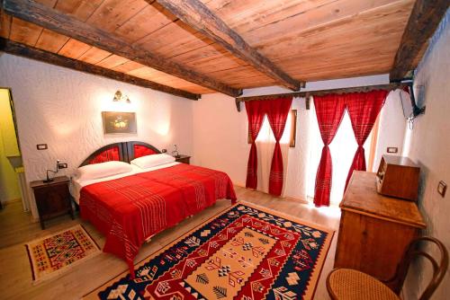 a bedroom with a red bed and red curtains at Hotel Tradita in Shkodër