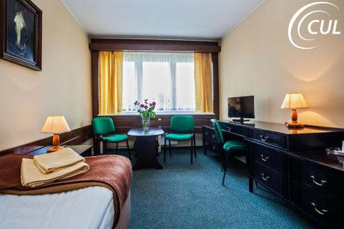 Habitación de hotel con cama, escritorio y sillas en Olimpia, en Poznan