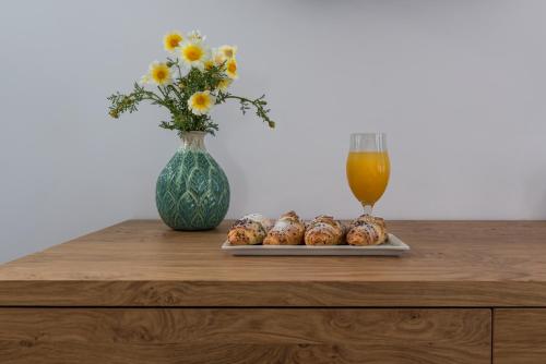 a table with a glass of orange juice and a vase with flowers at Anteliz Suites in Fira