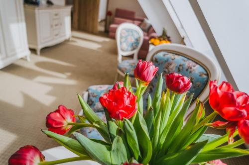 a table with a vase of red flowers and two chairs at Hotel Paryski Art & Business Zakopane - Basen Jacuzzi Sauna Małpi Gaj in Zakopane