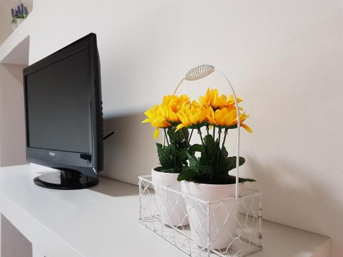 escritorio con monitor de ordenador y flores amarillas en Ermes Siracusa, en Siracusa