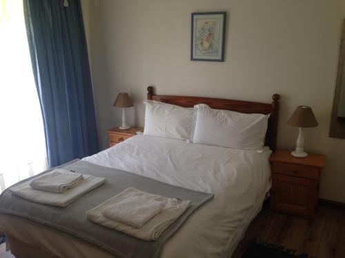 a bedroom with a bed with two towels on it at Blue Fern of Knysna in Knysna