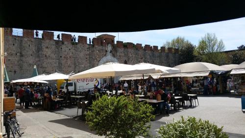 a market with tables and umbrellas in front of a brick wall at Hotel Il Giardino in Pisa