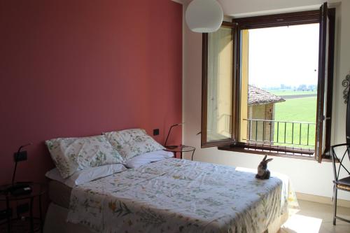 a bedroom with a bed and a window with a cat sitting on it at La casa dei gatti in Soragna