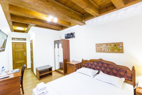 a bedroom with a large white bed and wooden ceilings at Hotel Volida Boutique in Bukhara