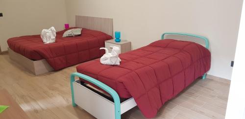 2 posti letto in una camera con lenzuola rosse e asciugamani bianchi di Cristallo Camere ad Alba