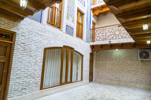an empty room with a brick wall and windows at Hotel Volida Boutique in Bukhara