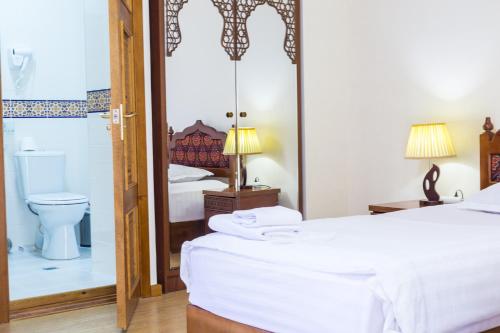 a bedroom with a bed and a toilet and a mirror at Hotel Volida Boutique in Bukhara