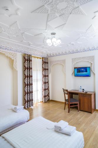 a hotel room with two beds and a desk at Hotel Volida Boutique in Bukhara