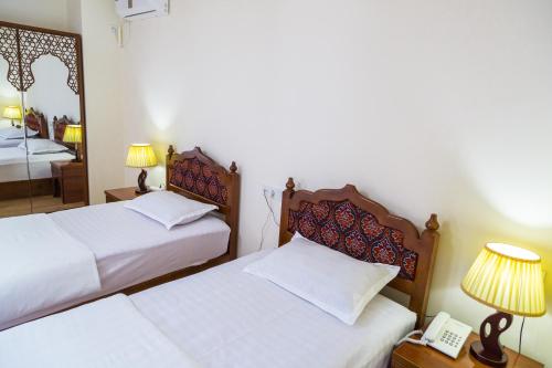 a bedroom with two beds and a telephone and a mirror at Hotel Volida Boutique in Bukhara