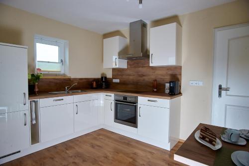 a kitchen with white cabinets and a sink at Hörnlestubn in Bad Kohlgrub